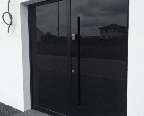 Schwarze Haustür mit Ganzglas-Oberfläche und langem Stoßgriff