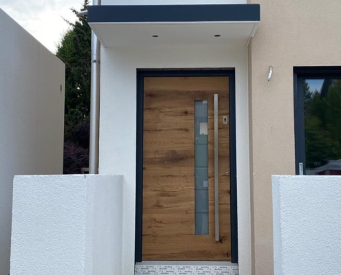 Haustür in Holzoptik mit Glasstreifen und Stoßgriff in anthrazitfarbenem Rahmen