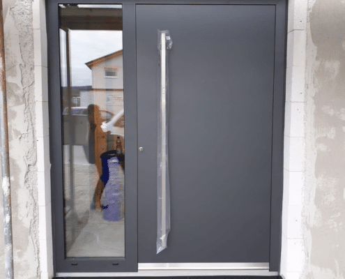 Anthrazitfarbene Aluminium-Haustür mit Glas-Seitenteil und gebogenem Edelstahl-Stoßgriff