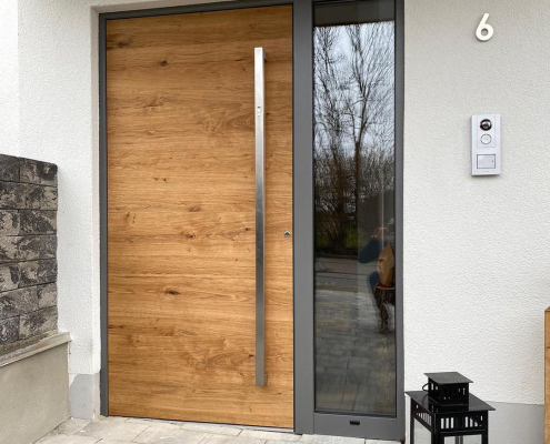 Haustür mit Holzoberfläche, langem Edelstahl-Stoßgriff und Glas-Seitenteil