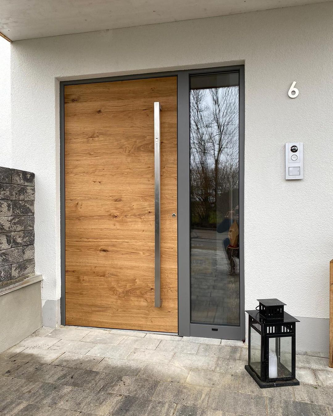 Haustür mit Holzoberfläche, langem Edelstahl-Stoßgriff und Glas-Seitenteil